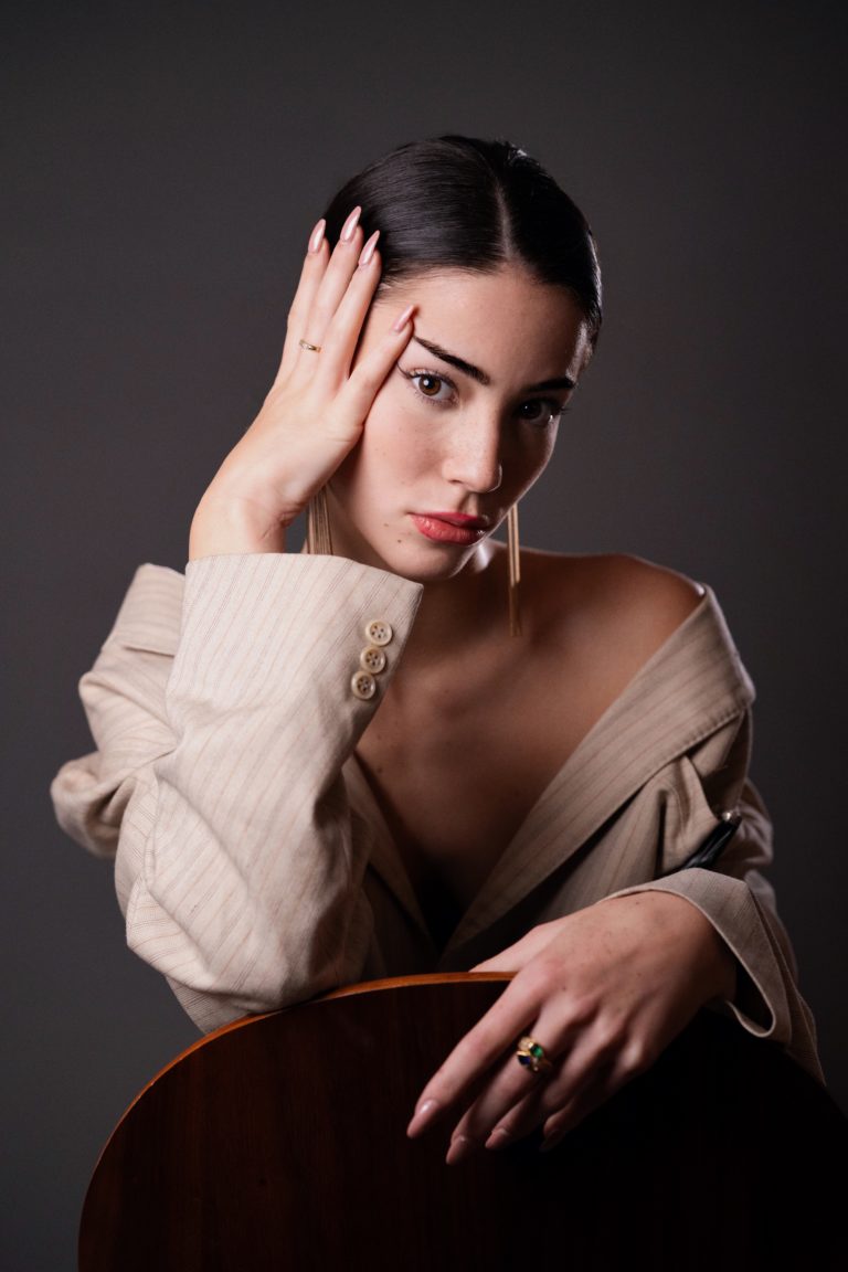 Une mannequin photographiée en studio sur fond gris. Elle est assise et porte une veste de costume.