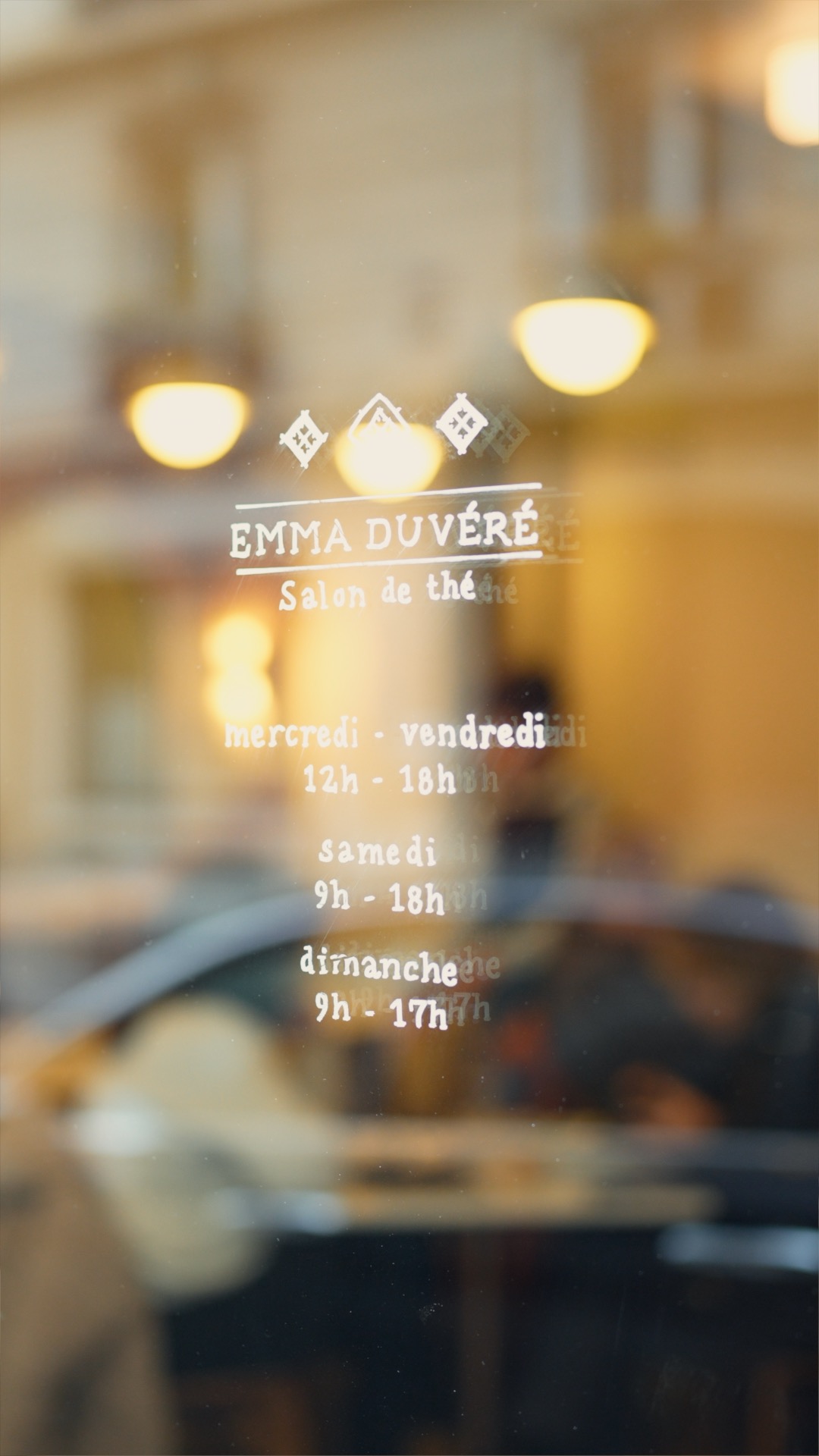 Extrait d'une vidéo présentant le salon de thé Emma Duvéré à Paris. Image de la porte du salon affichant les horaires d'ouverture.